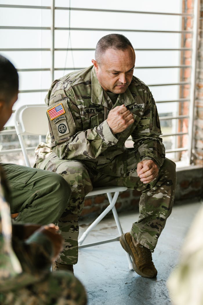 Services A military veteran in uniform participating in a group therapy session indoors.