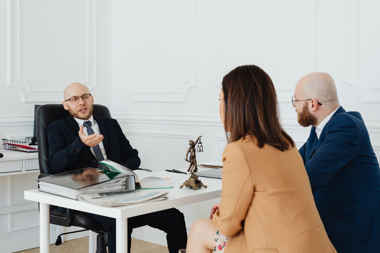 About Three adults in a formal business meeting discussing legal matters in an office.